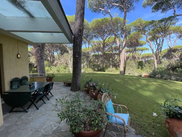 Luxurious Italian villa with a spacious outdoor terrace surrounded by mature trees and lush greenery, perfect for relaxation and outdoor dining.