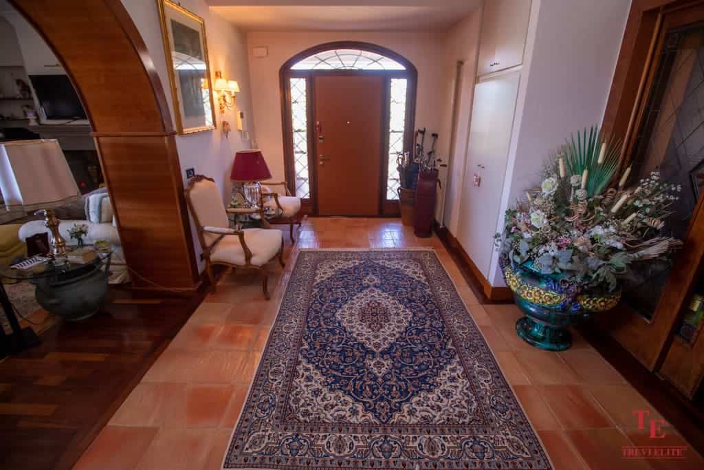 Elegant Italian villa entrance with classic decor, intricate rug, and floral arrangements, reflecting luxurious living standards.