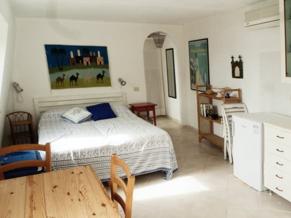Bright and airy Italian interior featuring a cosy bedroom with colourful artwork and natural light. Stylish furniture, modern decor, and a welcoming atmosphere highlight premium Italian real estate.