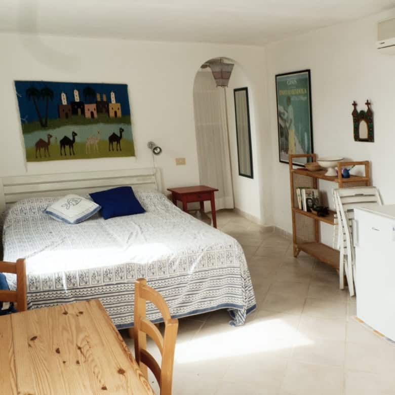 Bright and airy Italian interior featuring a cosy bedroom with colourful artwork and natural light. Stylish furniture, modern decor, and a welcoming atmosphere highlight premium Italian real estate.