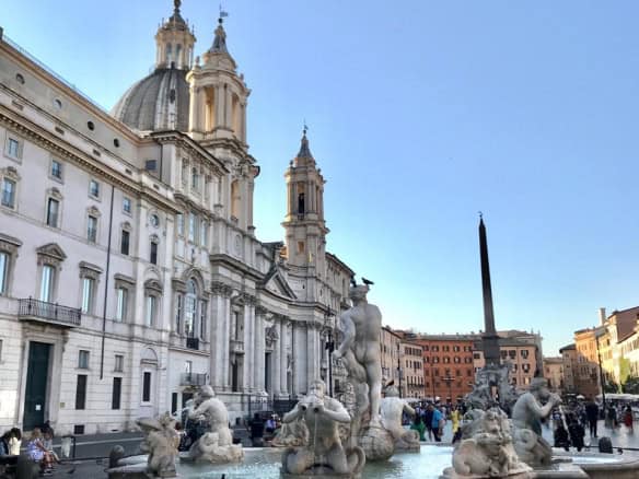 Eccentric fountain with classical statues in Piazza Navona, Rome, Italy, during daytime under clear blue sky.