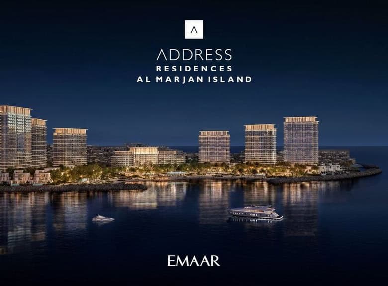 Luxurious residential high-rise buildings on Al Marjan Island at night, illuminated with city lights reflecting on the water, showcasing modern architecture and waterfront living opportunities.