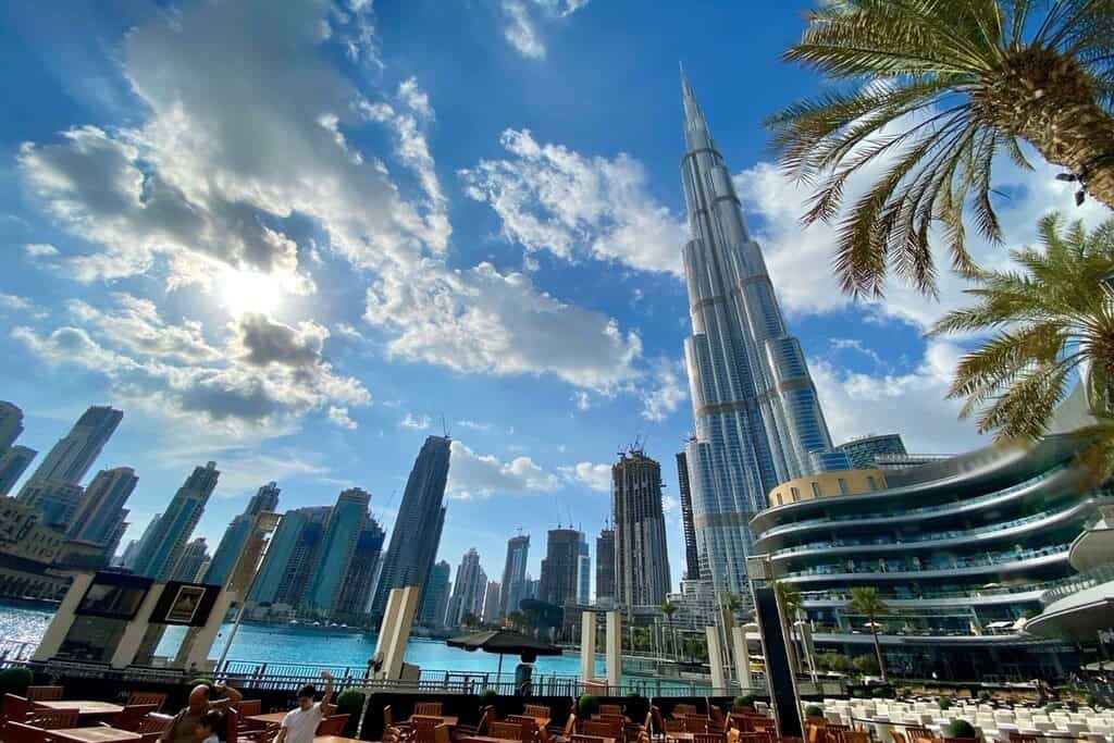 Burj Khalifa towering over Dubai skyline with waterfront view, blue sky, and modern architecture, showcasing luxurious real estate opportunities in the UAE.