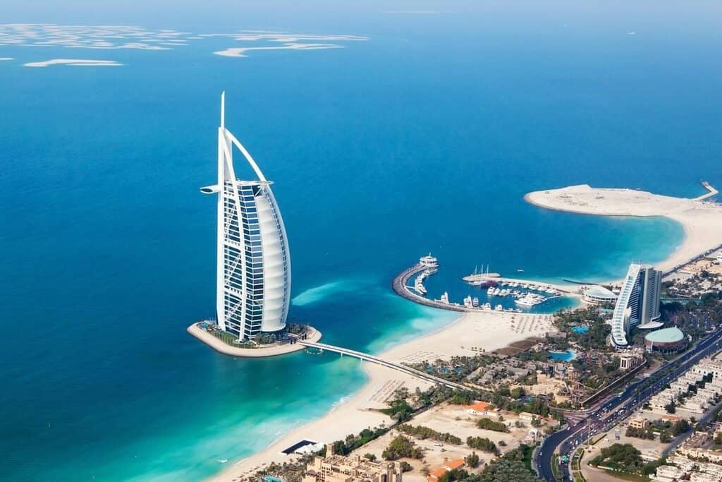 Modern luxury hotel with iconic sail-shaped architecture on Dubai’s waterfront. Stunning aerial view of Marina Bay offering exclusive real estate opportunities and breathtaking seaside scenery.