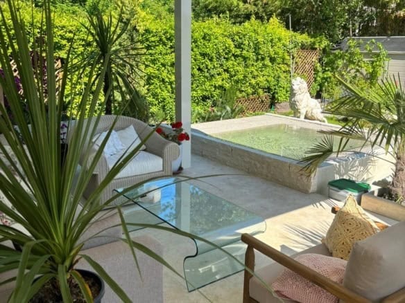 Modern outdoor living space featuring lush greenery, a small pool, and stylish furniture for relaxation. Perfect for enjoying the sunny Italian climate and garden views.