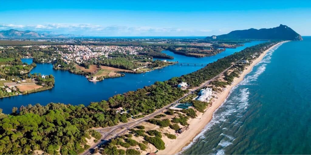 Breathtaking aerial view of Italian seaside coastline with sandy beaches, lush greenery, and azure waters, showcasing luxury real estate opportunities along the coast. For luxury connoisseurs - Trevi Elite.