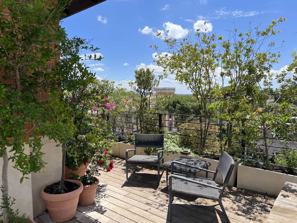 Lush rooftop terrace with vibrant potted plants, comfortable seating area, and cityscape views under a bright blue sky, perfect for relaxing and enjoying outdoor living.