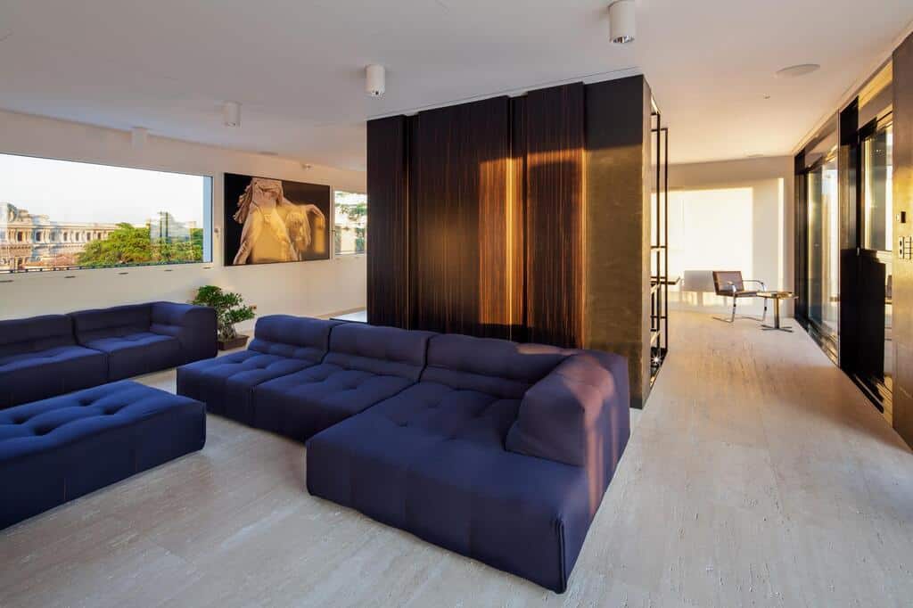 Luxurious modern interior of an Italian high-end apartment with sleek sofas, contemporary art, and floor-to-ceiling windows offering city views.