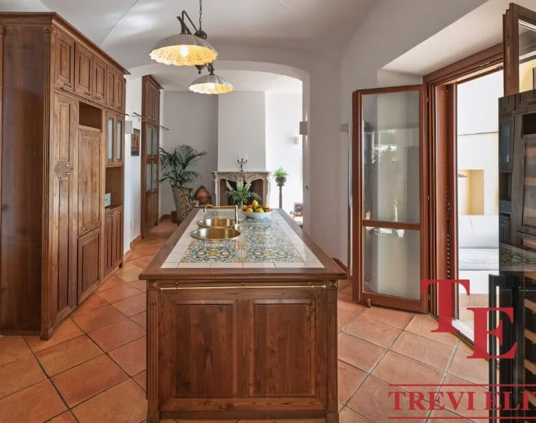Modern rustic kitchen with wooden cabinetry, tiled countertops, and sunlit courtyard access, ideal for elegant Italian living.