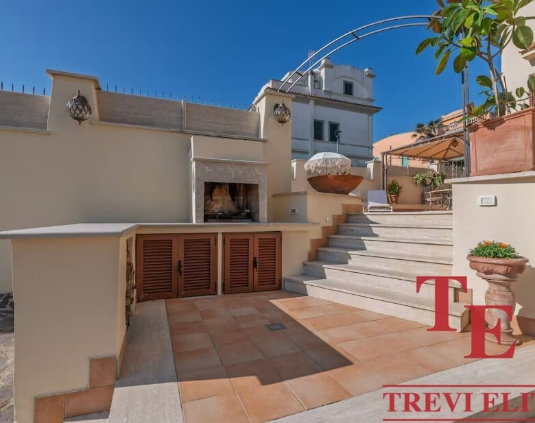 Elegant rooftop terrace with outdoor fireplace, ceramic tiles, and stylish potted plants in a luxurious Italian property by Trevi Elite. Perfect for entertaining in sophisticated style.