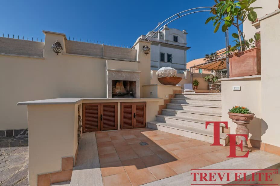 Elegant rooftop terrace with outdoor fireplace, ceramic tiles, and stylish potted plants in a luxurious Italian property by Trevi Elite. Perfect for entertaining in sophisticated style.