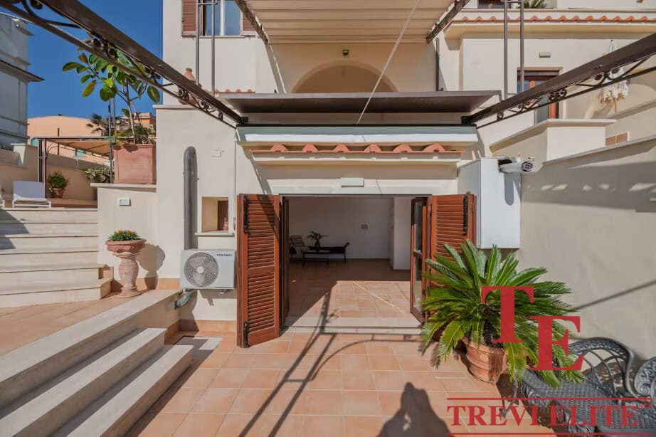 Elegant Italian townhouse terrace with terracotta flooring, lush potted plants, and stylish shutters; perfect for outdoor living.