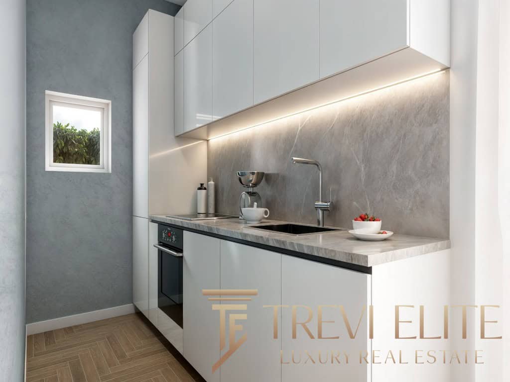 Modern minimalist grey and white kitchen with sleek cabinets, under-cabinet lighting, and a small window overlooking greenery, showcasing luxurious design for Italian high-end properties.