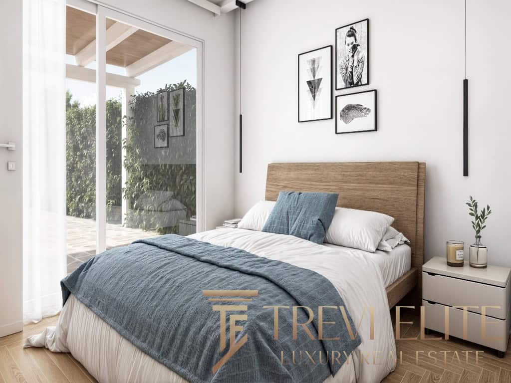 Stylish modern bedroom with minimalist decor, natural light, wooden accents, and elegant artwork, part of a luxurious Italian property offered by Trevi Elite.