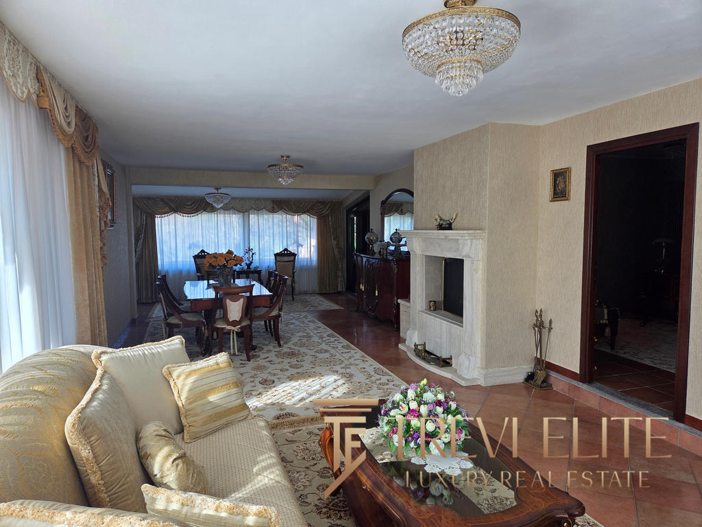 Elegant Italian living room with luxurious furnishings, ornate chandelier, and classic decor, featuring a spacious open-plan layout with a dining area and fireplace, perfect for upscale real estate listings.