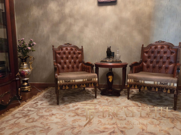 Luxurious antique-style armchairs with tufted leather upholstery and ornate wooden details in a classic Italian interior setting.