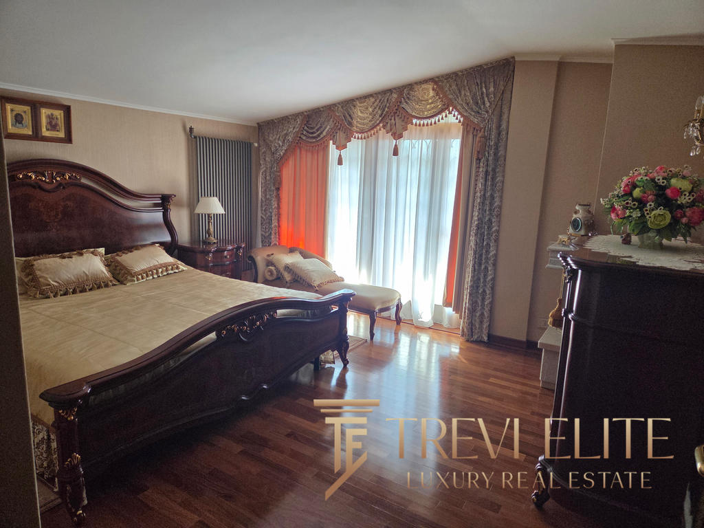 Elegant antique bedroom featuring a large wooden bed with intricate carvings, a vintage chaise lounge, ornate curtains, and polished wooden floors, showcasing luxurious Italian real estate.