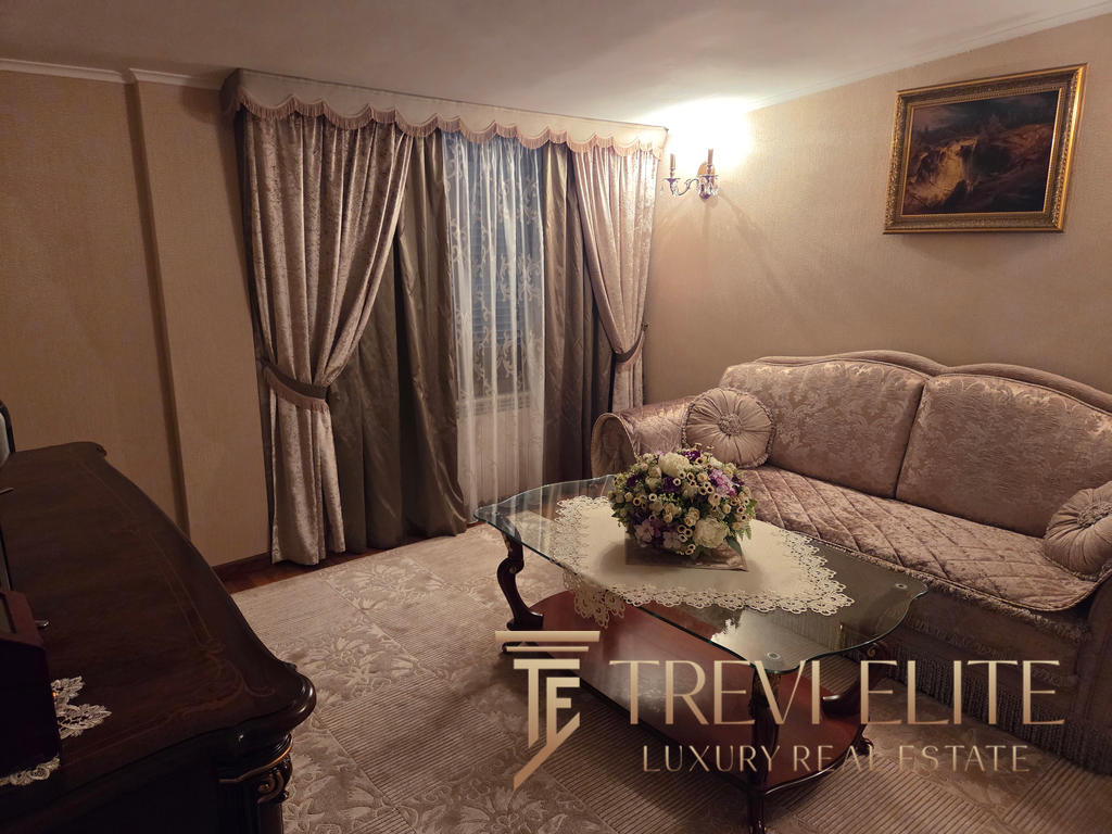 Elegant living room interior with luxurious traditional furniture, floral curtains, and a bouquet of fresh flowers on glass coffee table, ideal for high-end Italian real estate properties.