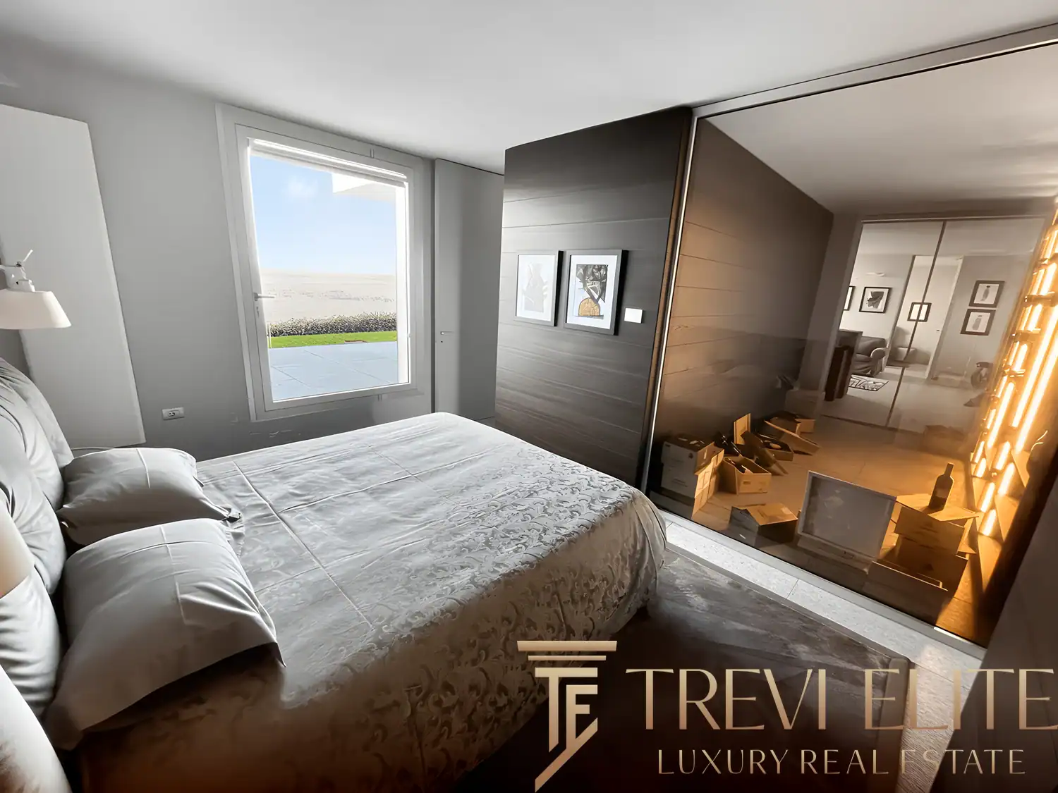 Minimalist bedroom with neutral linens and a wide window overlooking the lake.