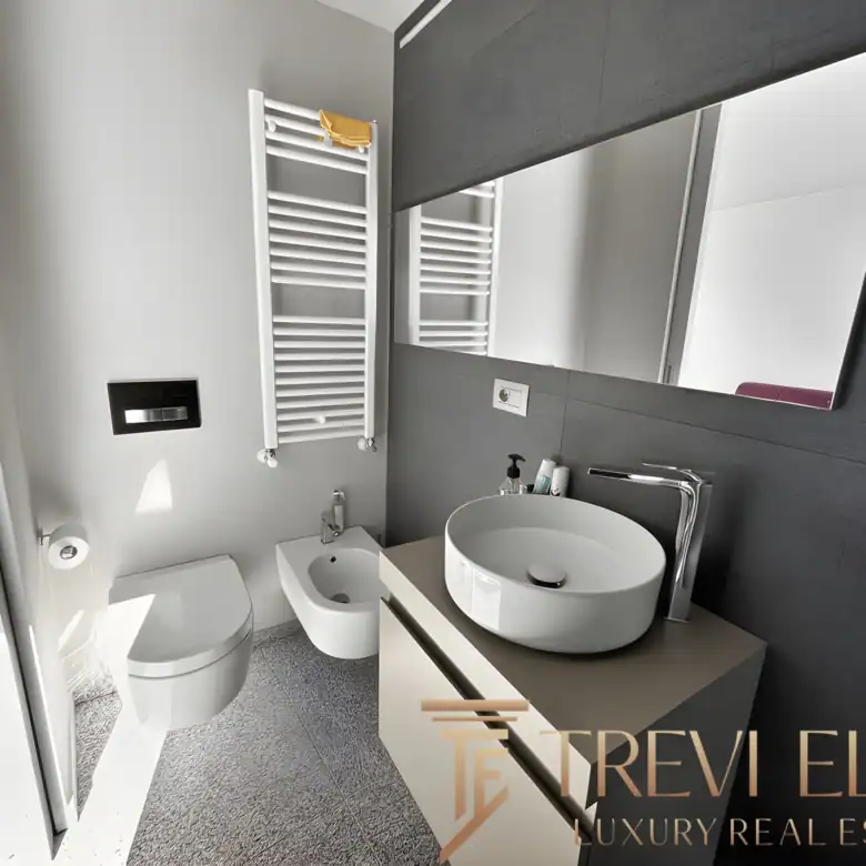 Modern bathroom with a round vessel sink, grey tiling, and minimalist mirror.