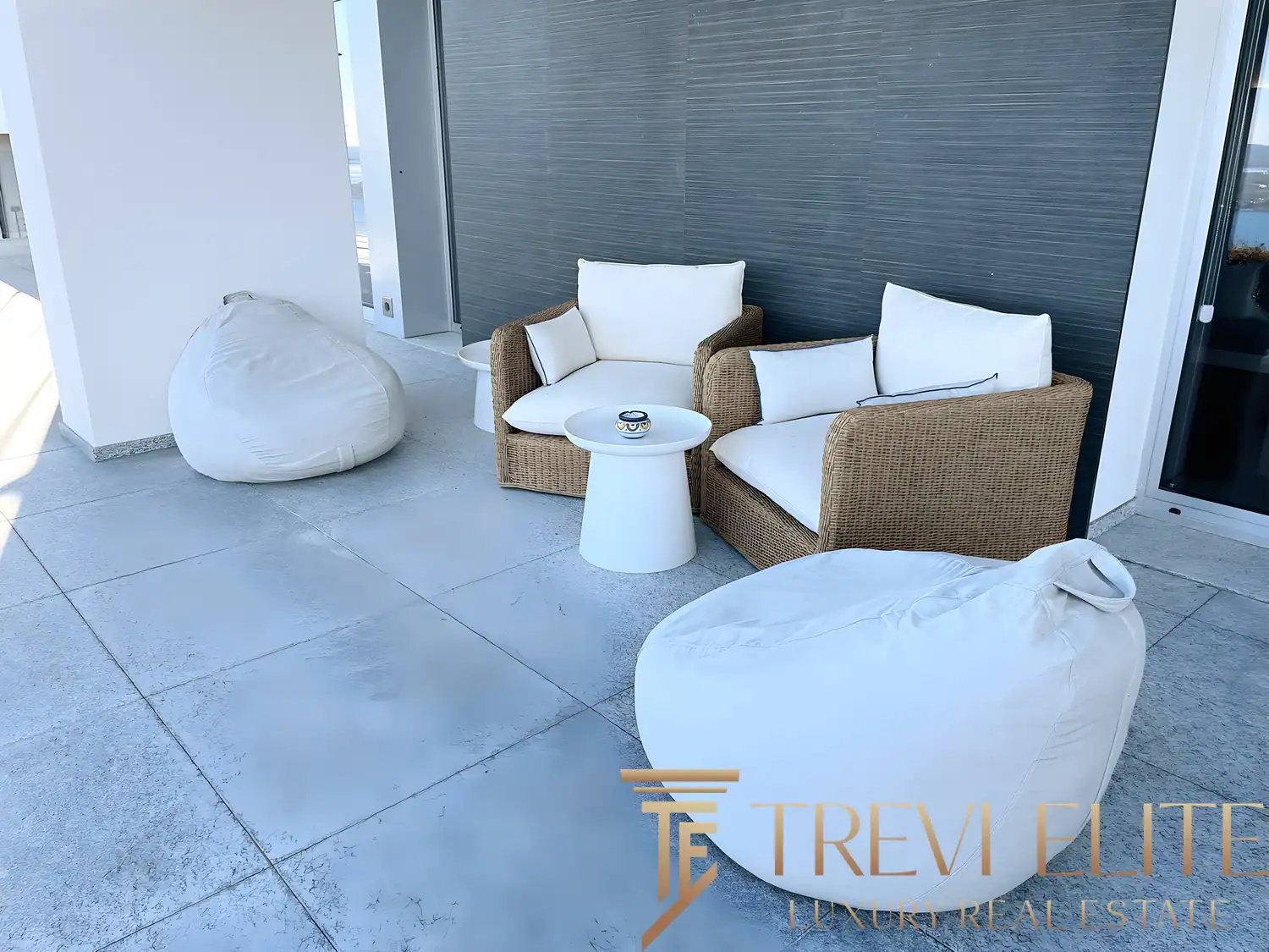 Outdoor lounge area with modern white beanbags and wicker furniture.