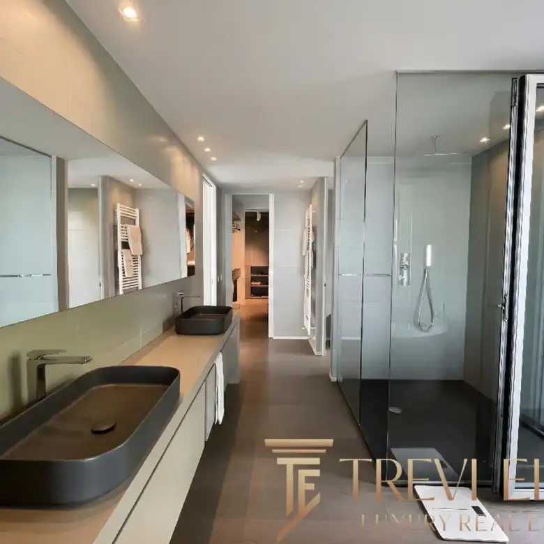 Modern bathroom with a long black floating vanity and glass shower.
