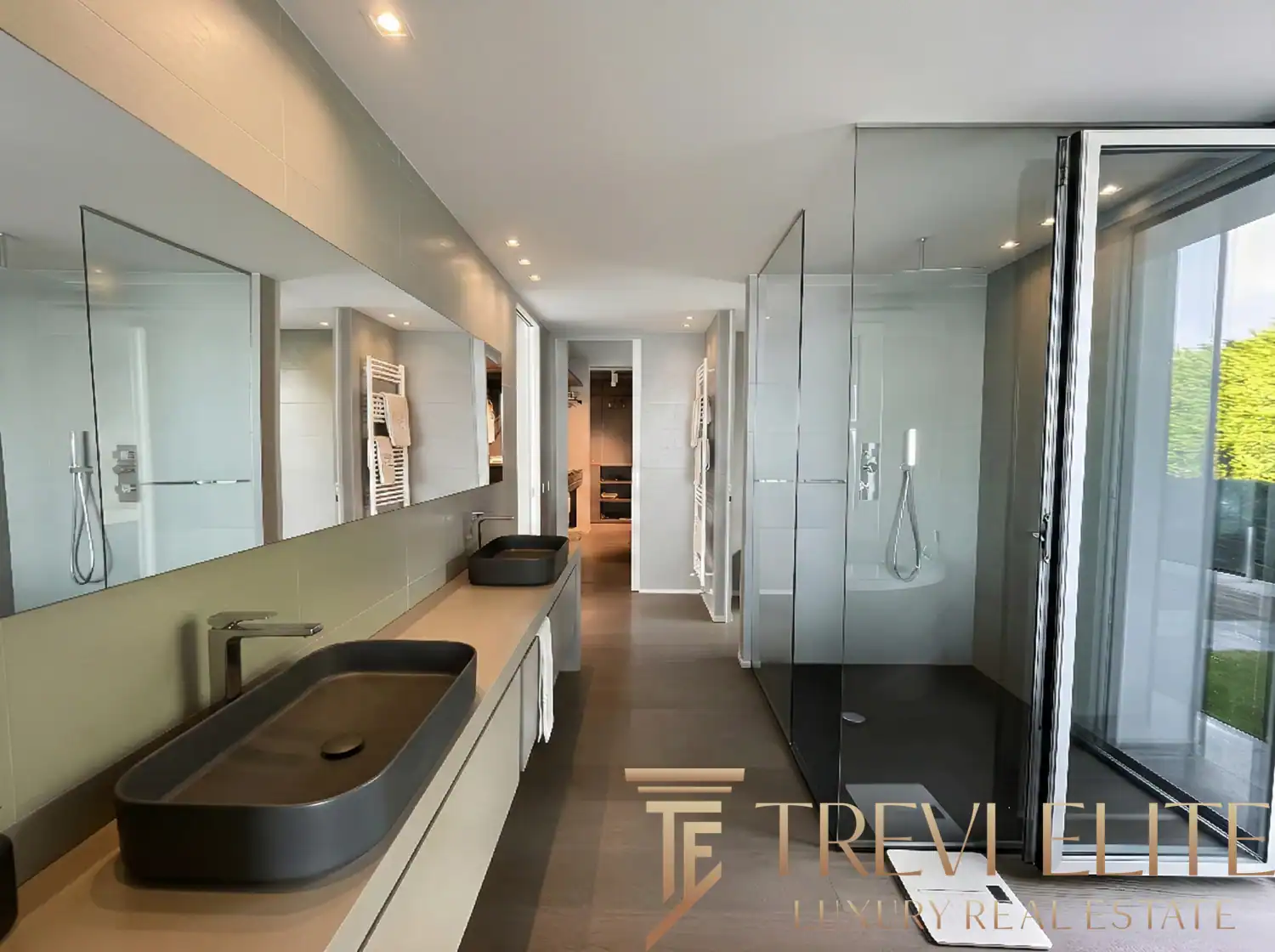 Modern bathroom with a long black floating vanity and glass shower.