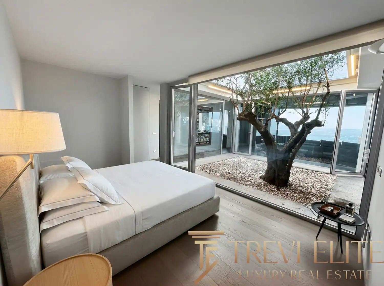 Cozy bedroom with warm lighting and a view of the courtyard tree.