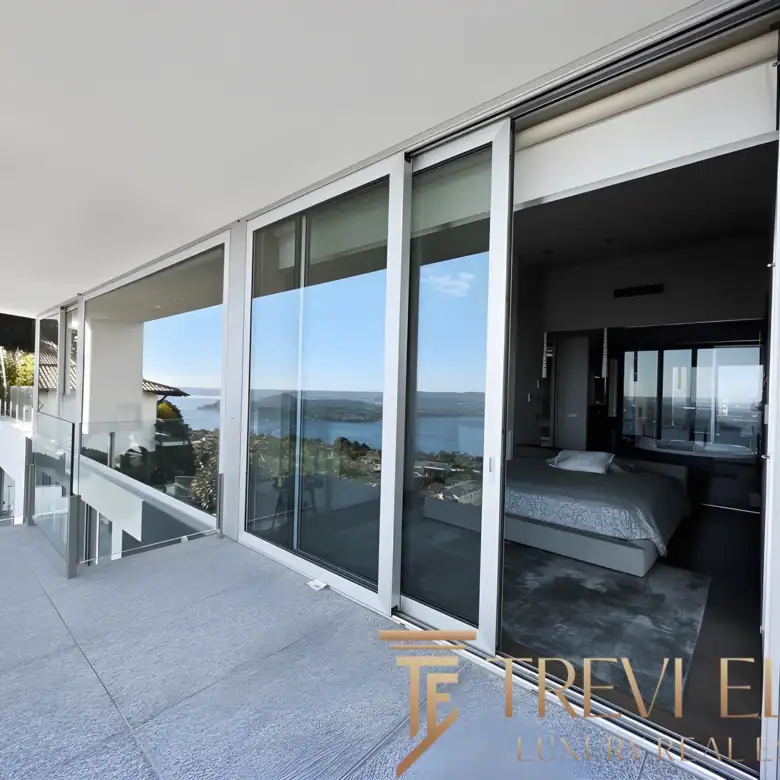 Wide terrace view with glass railings and a clear vista of the Italian lake district.