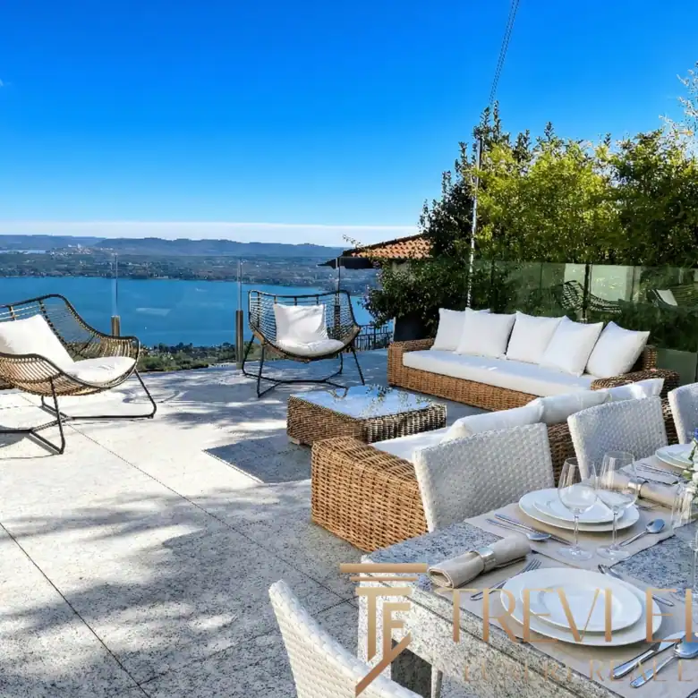 Outdoor dining terrace with a set table and white floral arrangements.