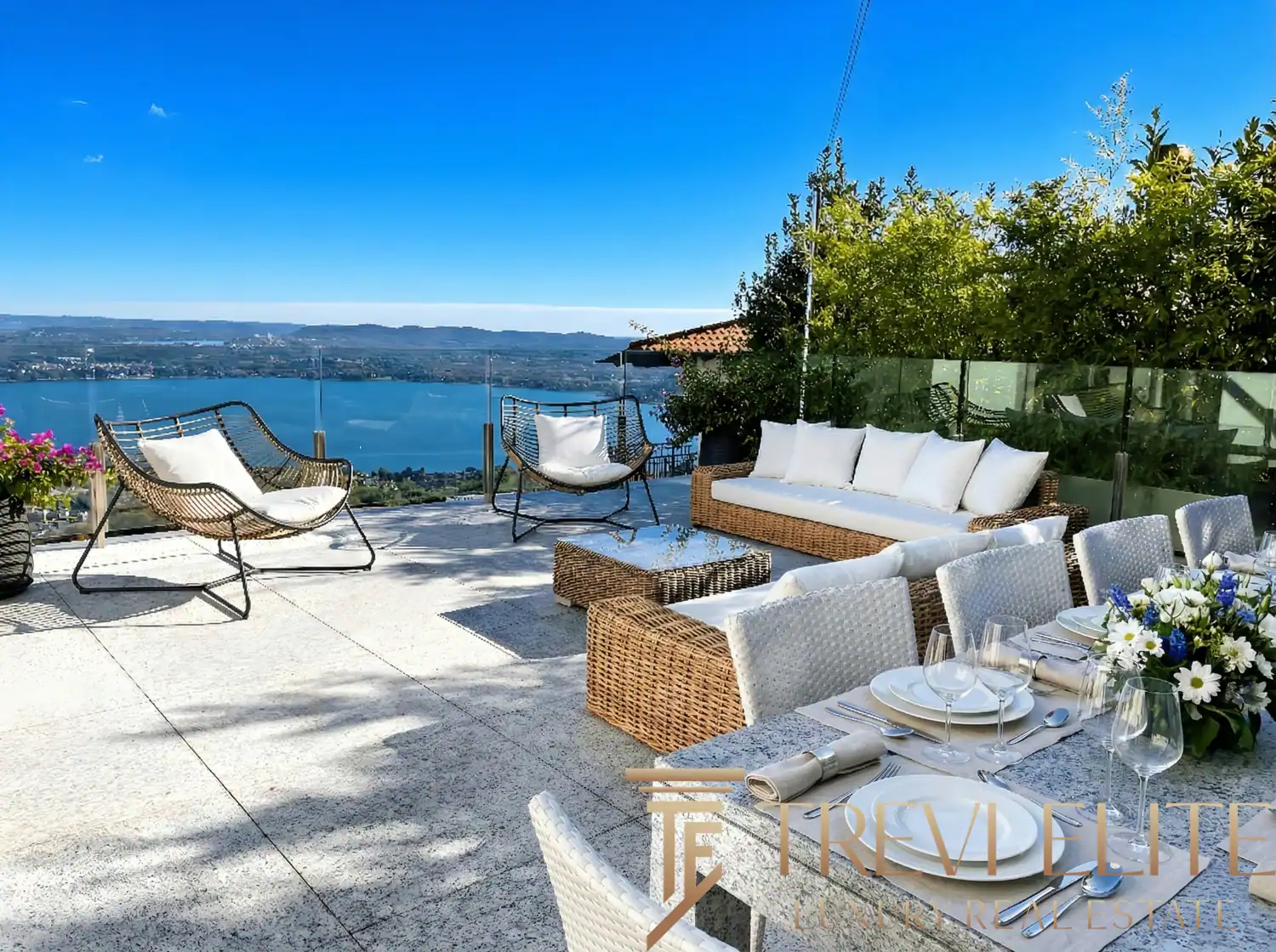 Outdoor dining terrace with a set table and white floral arrangements.