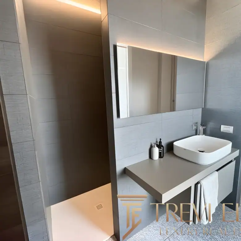 High-end bathroom with a white vessel sink, large mirror, and warm lighting.