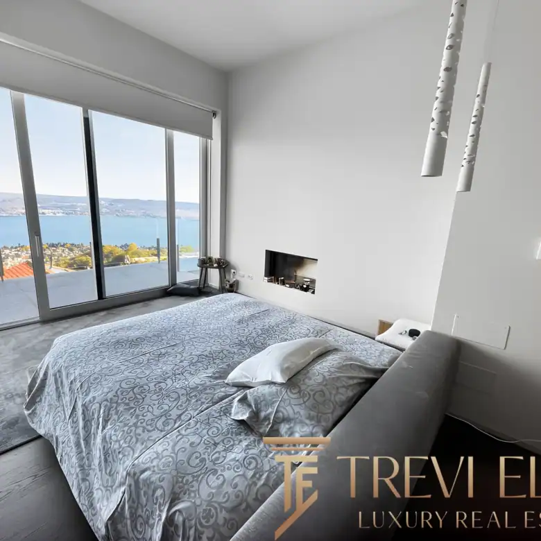 Modern bedroom with grey bedding and large sliding glass doors to the balcony.