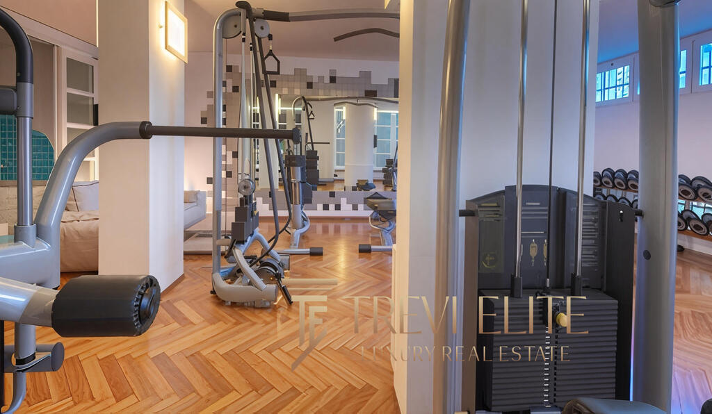 Modern gym interior with advanced fitness equipment and wooden flooring, showcasing a luxurious Italian real estate setting by Trevi Elite.