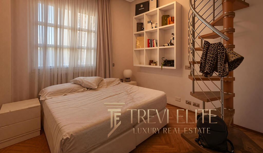 Modern bedroom with large window, beige curtains, and minimalist decor, featuring a white double bed, a bedside table, and a unique spiral staircase leading to an upper level, highlighting luxurious Italian real estate.