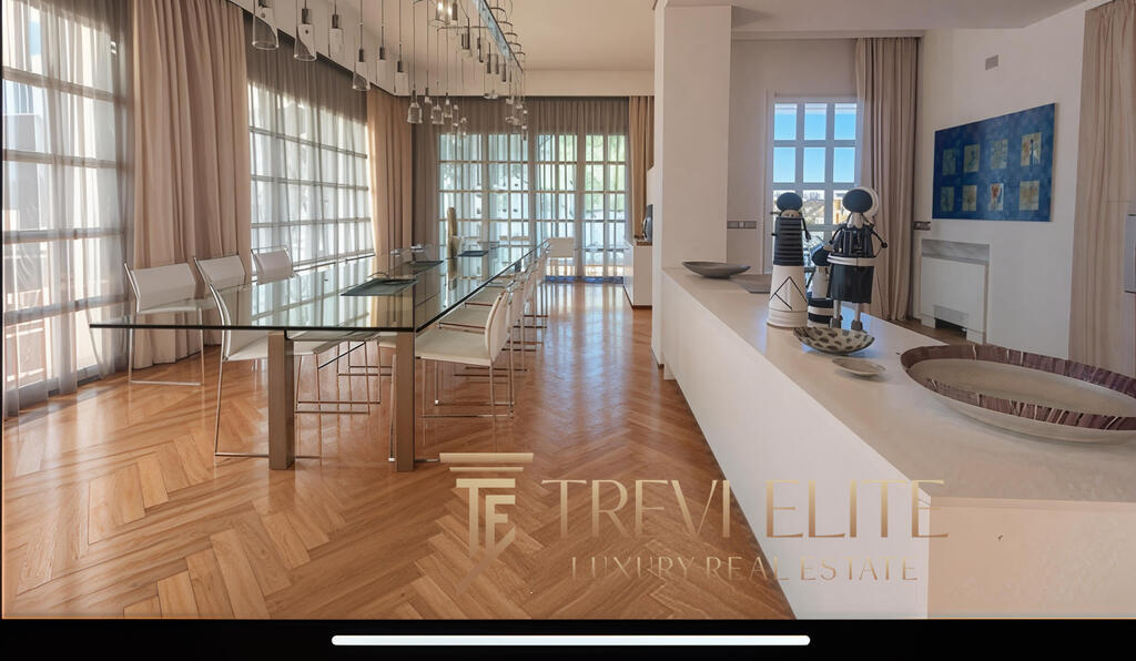 Luxurious dining area with large windows, sheer curtains, modern glass table, and elegant white chairs in a high-end Italian property by Trevi Elite.