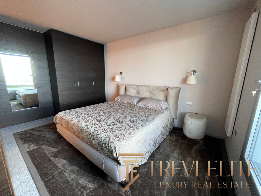Contemporary bedroom with a large bed, stylish headboard, and modern lighting fixtures in a luxurious Italian property.