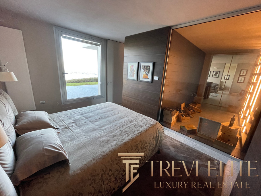 Luxurious bedroom with minimalist design, overlooking scenic outdoor view, featuring elegant decor, soft lighting, and a modern glass partition separating the sleeping area from the living space.