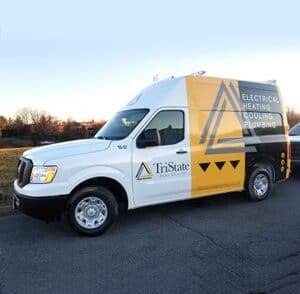 A White And Yellow Service Van With &Quot;Electrical Heating Cooling Plumbing&Quot; Text And The &Quot;Tristate&Quot; Logo Is Parked On A Road. The Sky Is Clear And Trees Are Visible In The Background.
