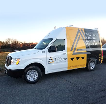 A White And Yellow Service Van With &Quot;Electrical Heating Cooling Plumbing&Quot; Text And The &Quot;Tristate&Quot; Logo Is Parked On A Road. The Sky Is Clear And Trees Are Visible In The Background.