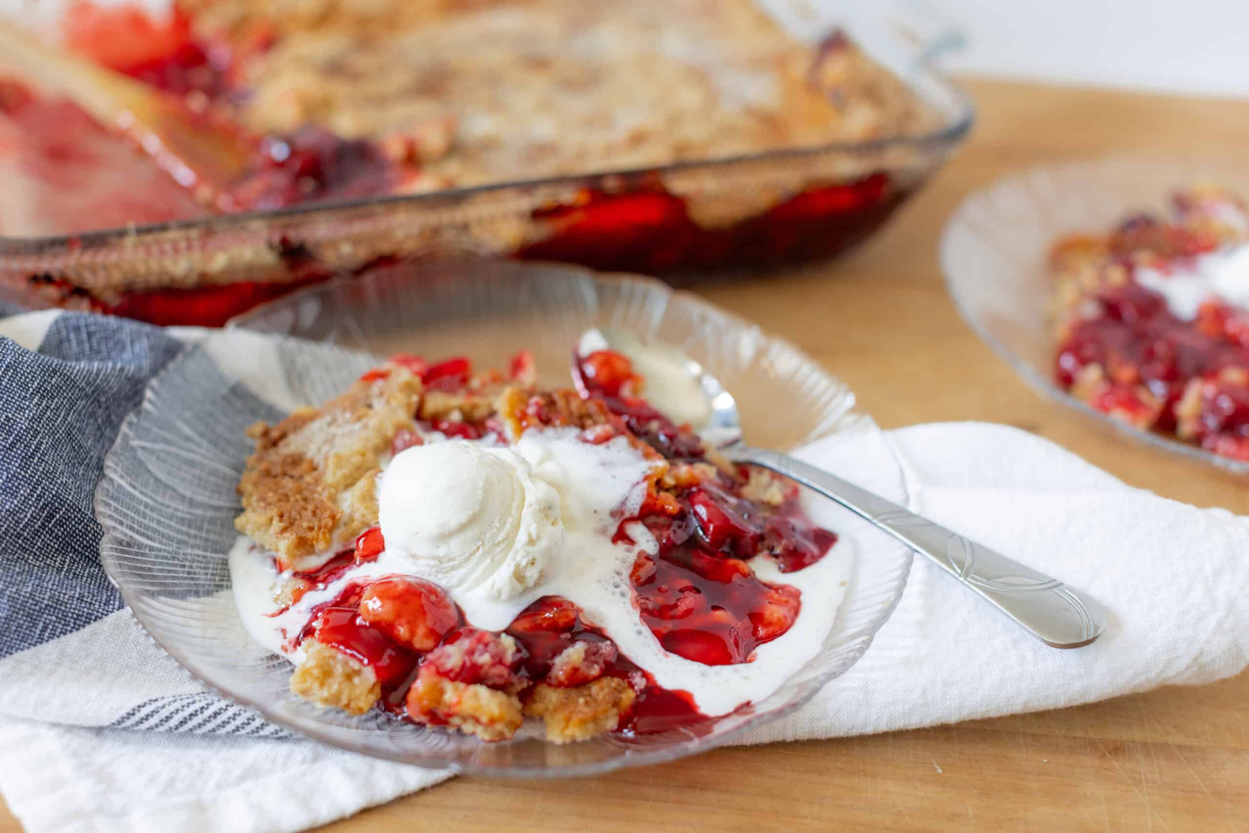 Fresh cherry crumble dessert garnished with vanilla ice cream served on a glass plate for a delicious, homemade berry fruit dessert.