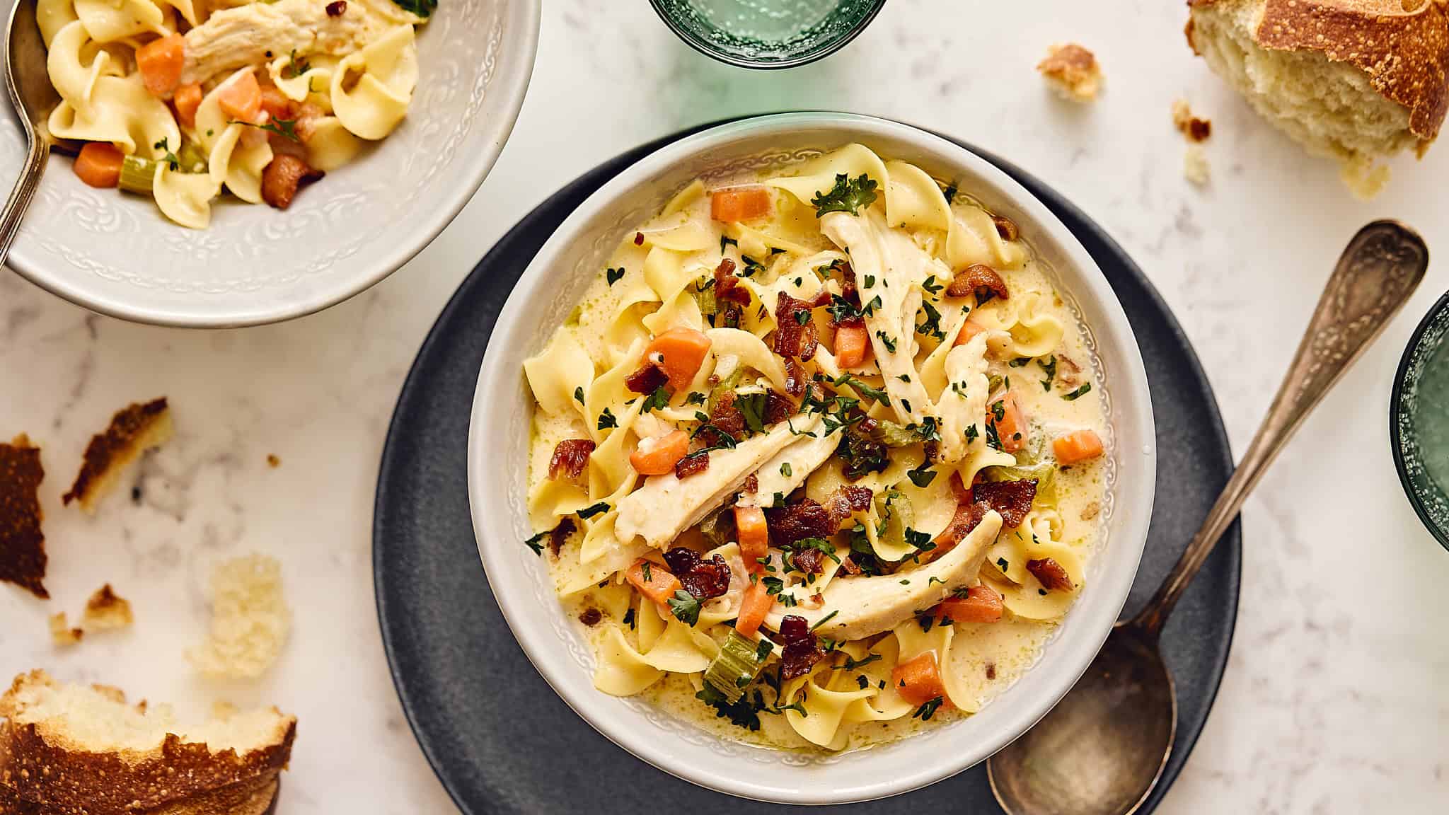 Creamy chicken and vegetable noodle soup with bacon, fresh herbs, and tender pasta served in a white bowl. Perfect for cozy meals and easy comfort food recipes.