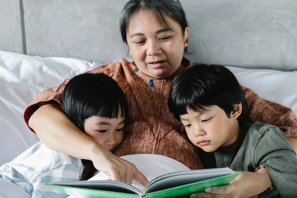 gentle parenting of a woman reading a book to two children in bed