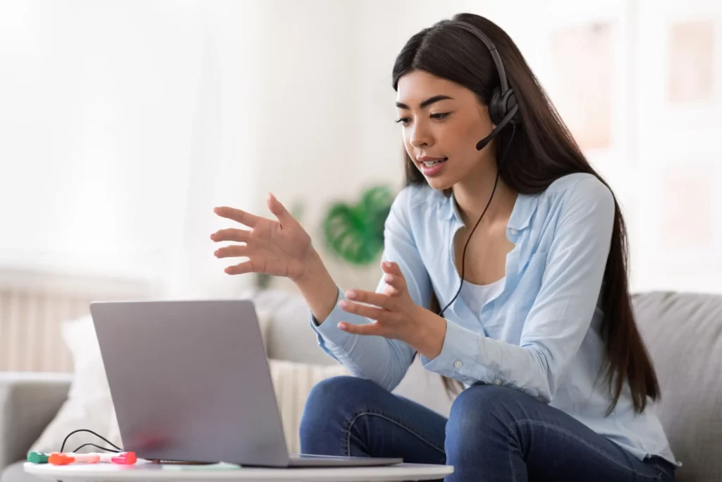 female tutor with headset and mic teaching in front of laptop