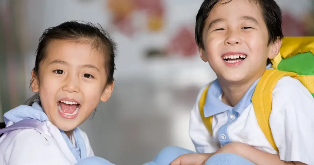 two young children sitting on the floor with backpacks