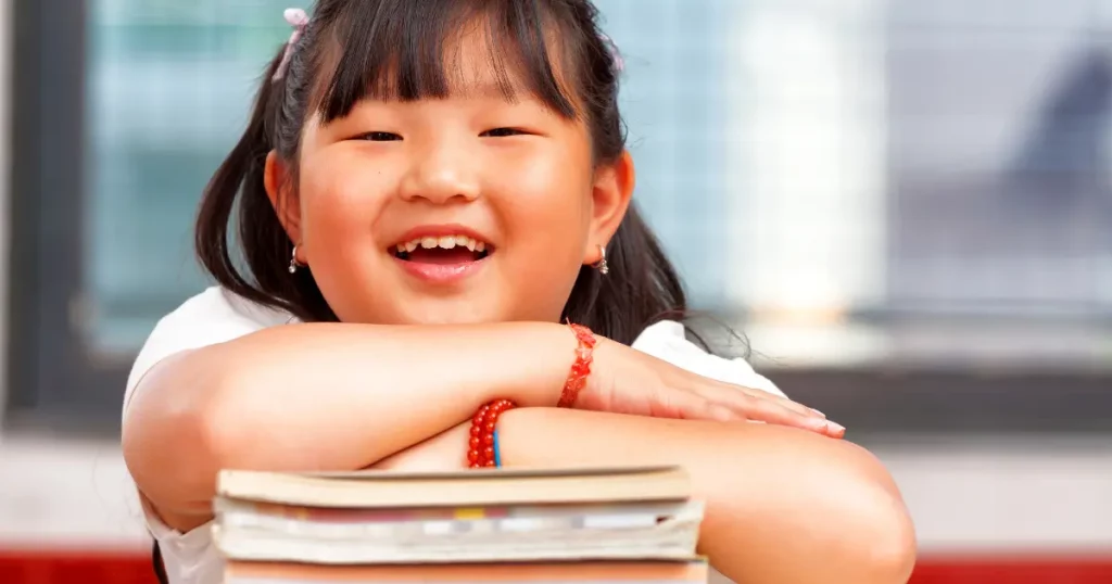 a girl is smiling while holding a stack of books