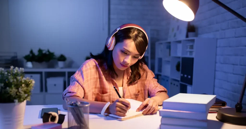 a person is sitting at a desk with headphones on | tuitioncentre sg