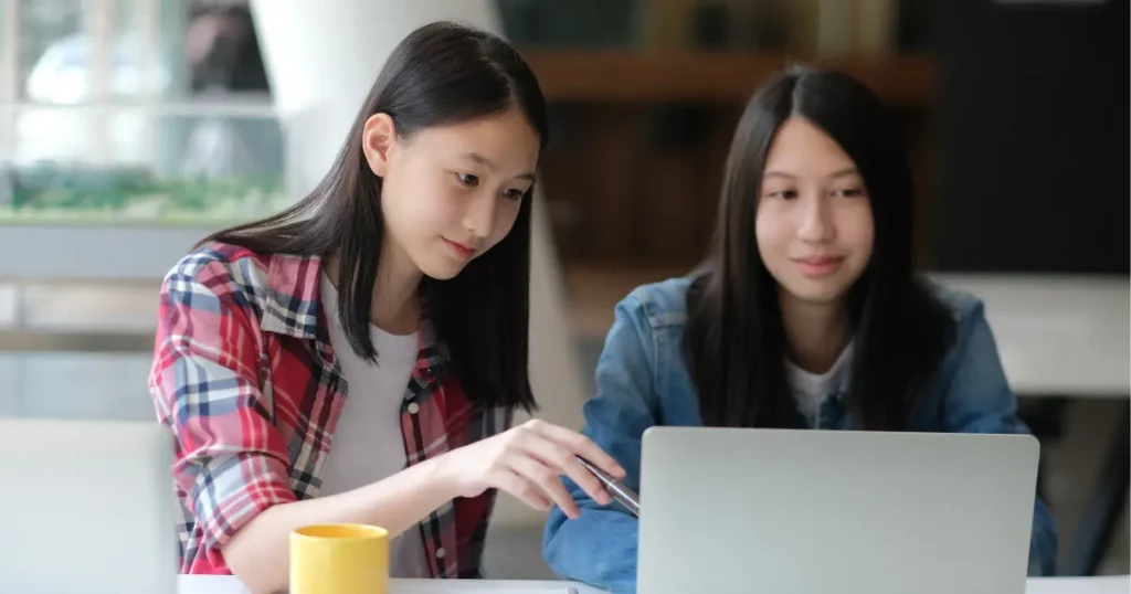 two individuals sitting at a table with laptops | tuitioncentre sg