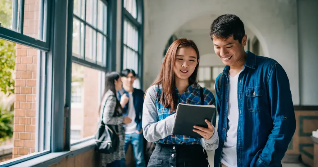 two people standing in a hallway looking at a tablet | tuitioncentre sg
