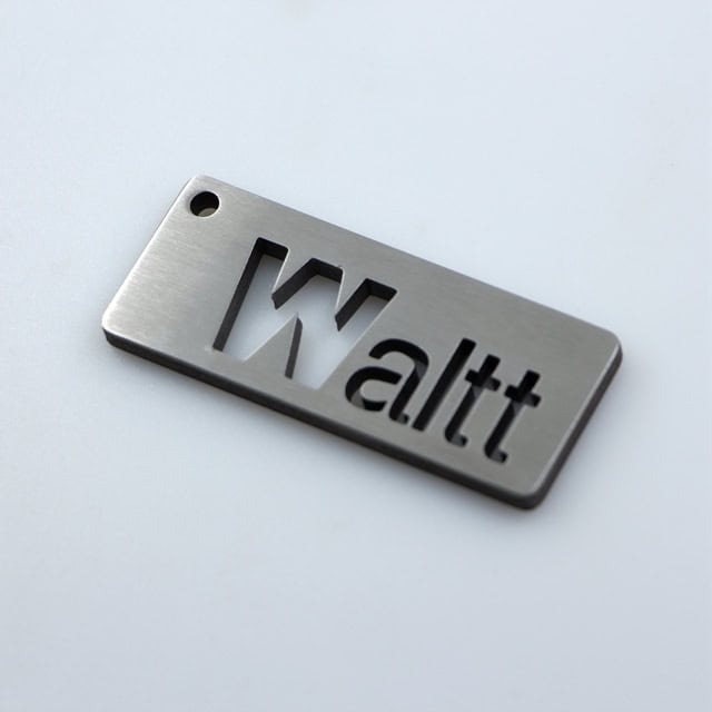 Stainless steel car part keychain with "Walt" cutout, perfect for auto enthusiasts and branded accessories.
